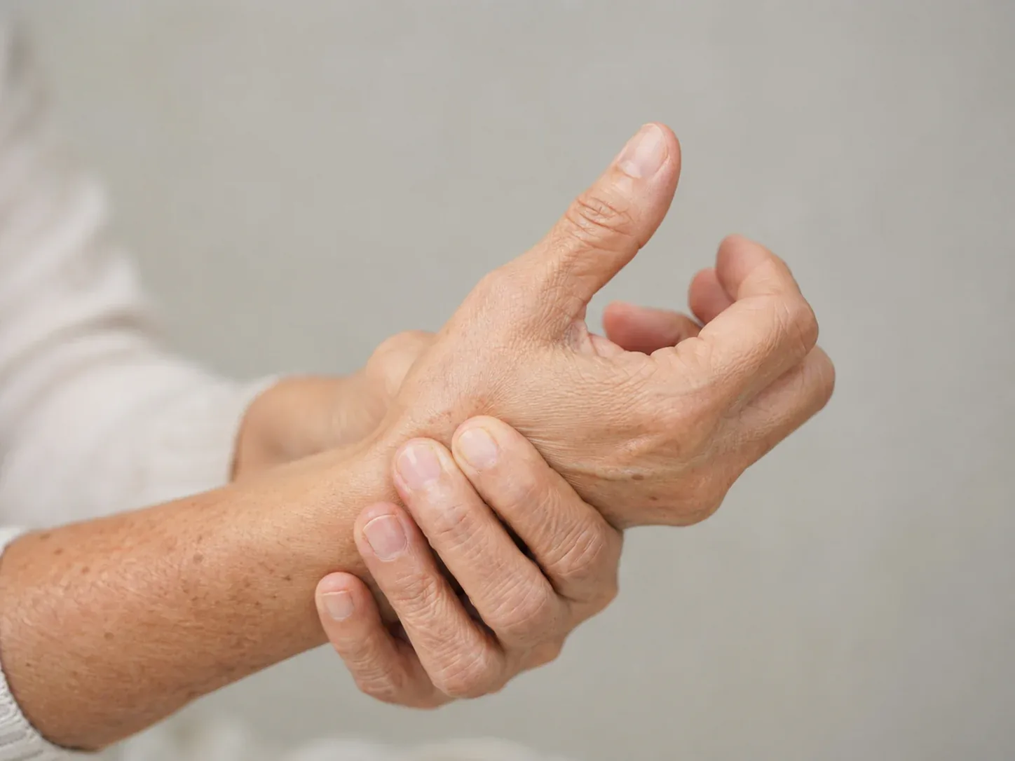 Older adult holding the base of the thumb consistent with thumb CMC arthritis