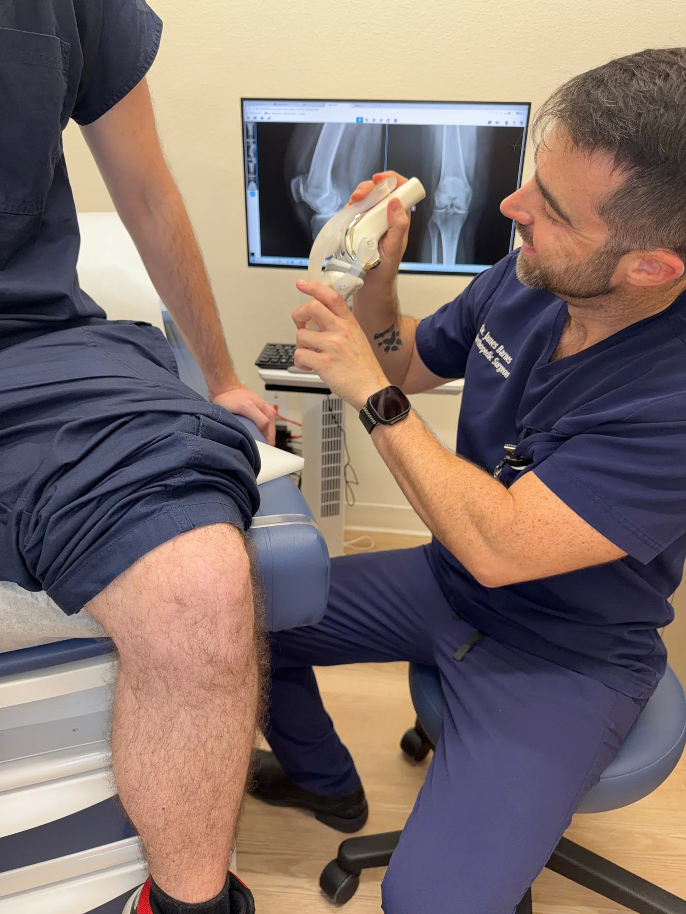 Dr. Barnes discussing joint replacement options with a patient using a knee replacement model